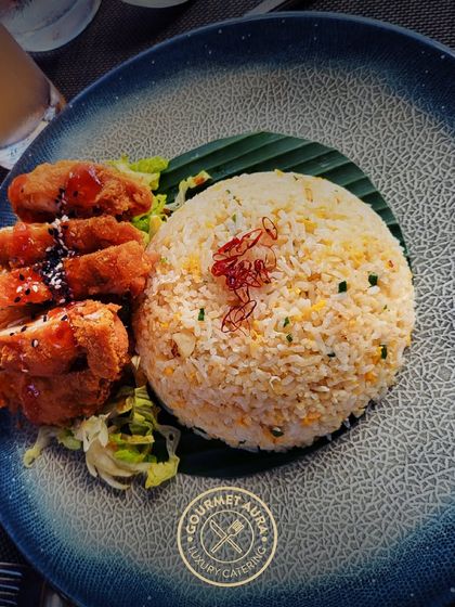 A serving of crispy chicken katsu alongside fragrant fried rice on a banana leaf. A satisfying and popular dish from our Pan-Asian menu.