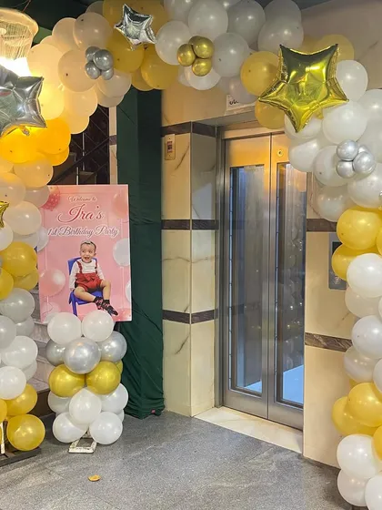 A grand entrance for a first birthday party with a gold and white balloon arch and a personalized welcome sign.