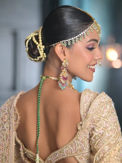 A beautiful view of the back, showcasing the intricate pearl-adorned bun that complements this ethereal ivory lehenga. Every detail is considered.