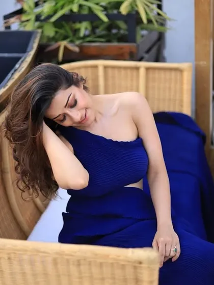 A beautiful shot of an actress during a photoshoot. The makeup is kept natural and glowing to complement the vibrant blue outfit and daylight setting.