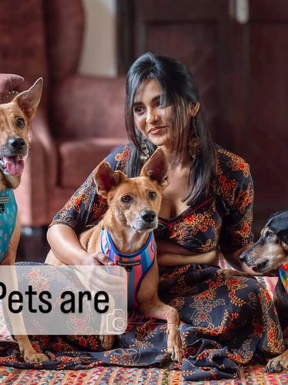 A woman surrounded by her four indie dogs on a colorful rug. This at-home portrait is a vibrant celebration of her rescued family.