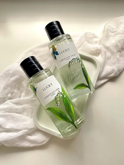 An example of my hand-painted customization work on a Christian Dior fragrance bottle. For this 'Lucky' perfume, I painted delicate lily of the valley illustrations to complement the scent's notes, creating a personalized and luxurious gift.