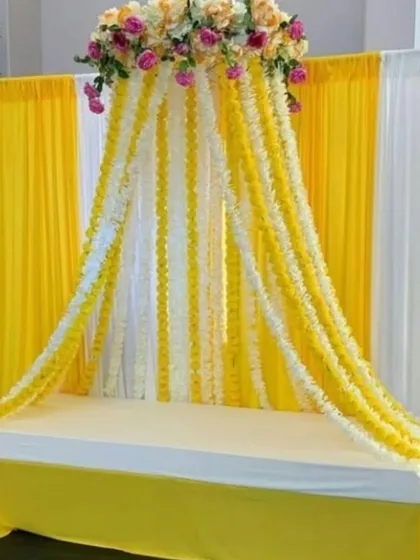 A unique canopy-style seating arrangement for a Haldi ceremony. I created this look with cascading garlands of yellow and white flowers flowing from a floral crown, providing a beautiful and immersive space for the bride or groom.