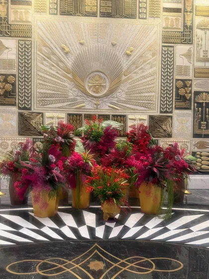 The collection of arrangements against the intricate gold and black wall creates a powerful visual statement. The repetition of color and form provides a sense of rhythm and grandeur.