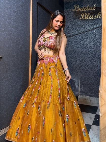 A full-length view of the yellow Haldi lehenga. The tiered skirt and colorful embroidery make it a fun and festive choice.