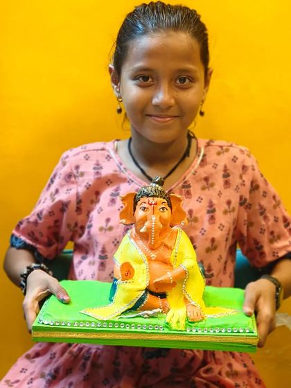 A young artist with her beautifully painted Ganpati idol. Our workshops provide a platform for everyone to express their devotion and creativity, resulting in unique masterpieces filled with personal touches.