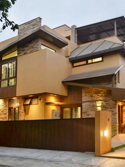 This modern rustic home, known as the 'Mountain Abode', captures the feeling of a mountainside retreat. The exterior lighting design highlights the texture of the stacked stone and the clean lines of the metal-clad roof against the evening sky.