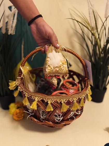 A hand holding one of our decorated wicker baskets for Sankranti, showing how easy and beautiful they are to gift.