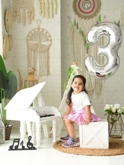 A proud three-year-old in our stylish boho studio setup. The silver balloon adds a festive touch to the neutral, textured background.