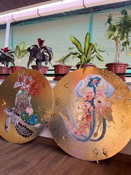 These large, circular art pieces were created for a boutique hotel in Goa, blending underwater life with local flora. Here, a jellyfish and a sea turtle are reimagined with floral elements, all set against a shimmering gold-leaf background.