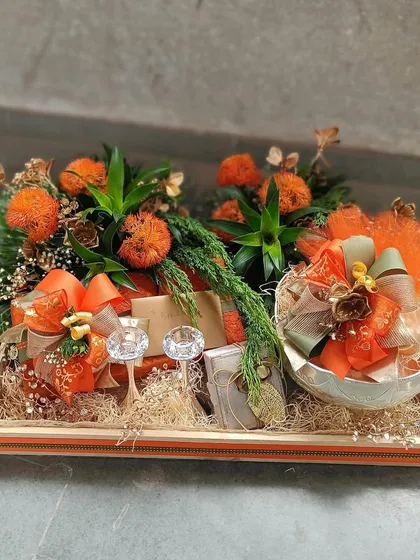 An autumn-inspired hamper featuring rich orange tones and natural textures. This arrangement includes two crystal glasses and other curated items, making it a warm and inviting gift for a housewarming or fall festival.
