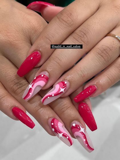 A playful and cosmic design in shades of red and pink. This set on coffin nails features abstract swirls and hand-painted white stars for a fun, retro feel.