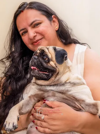 A warm and cozy portrait of a woman holding her pug. This image captures the comfort and affection that defines the bond with a beloved pet.
