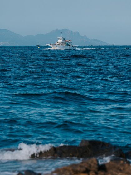 A yacht speeds across the blue water off the coast of St. Tropez. This image captures the luxury and leisure lifestyle associated with the South of France.