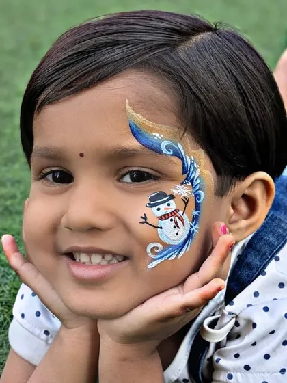 A happy child showing off her snowman face paint. This design is perfect for winter-themed parties or Christmas celebrations.