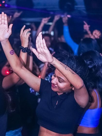 A guest with her hands up, feeling the music.