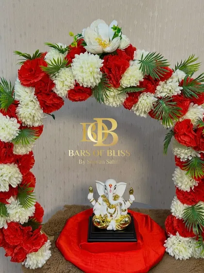 A simple and sweet floral ring for a small Ganpati idol. This arch of red and white artificial flowers provides a beautiful and respectful frame for your home pooja setup.