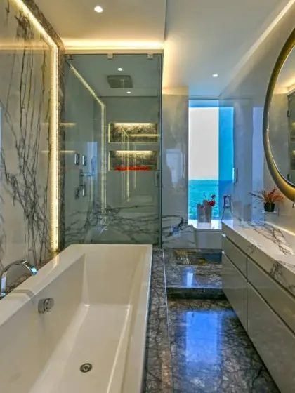 This bathroom is a sanctuary crafted from floor-to-ceiling marble. We integrated a freestanding bathtub, a glass-enclosed shower, and a custom vanity with backlit mirrors to create a space that feels like a private, five-star spa.