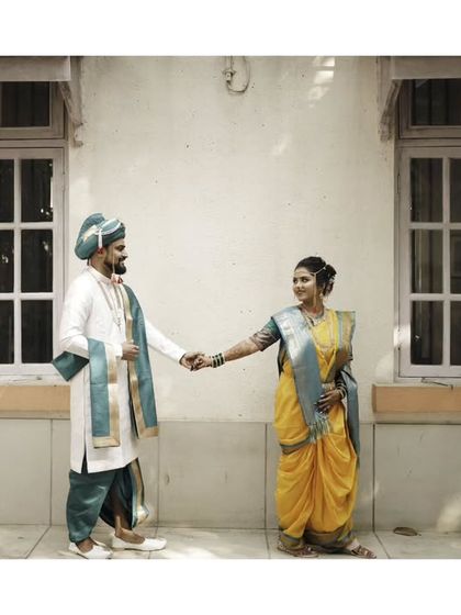 A classic portrait of the couple holding hands, set against a traditional wada-style building.