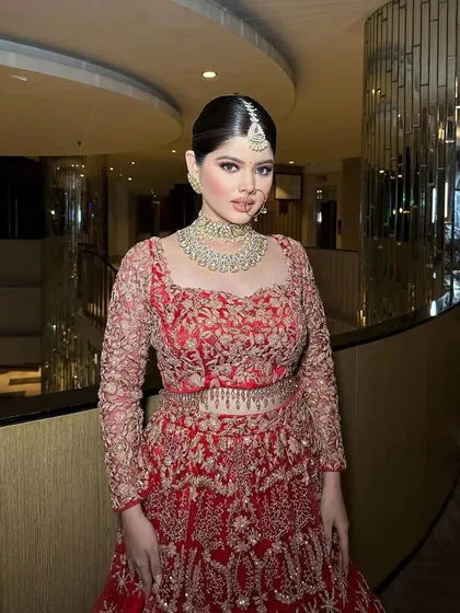 A full-length view of the red lehenga. The styling is minimalist yet elegant, allowing the beautiful craftsmanship of the outfit to shine.