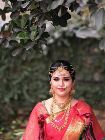 A radiant portrait of my bride Chinmayi. Her makeup features a classic red lip and defined eyes, perfectly complementing her red Kanjeevaram saree and gold temple jewellery.