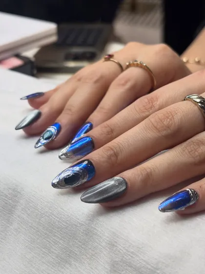 Another angle of the blue and silver chrome cat eye nails, showing how the design wraps around the nail. The combination of the electric blue and liquid silver creates a dynamic look that changes from every viewpoint.