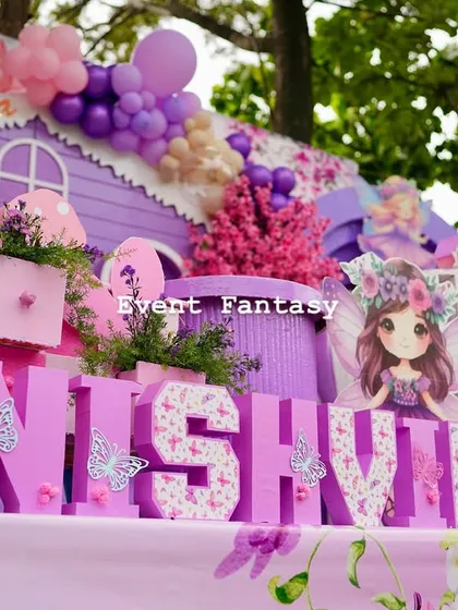 A detailed shot of the "NISHVIKA" name blocks, decorated with a floral pattern and butterflies, sitting in front of the whimsical fairy house.