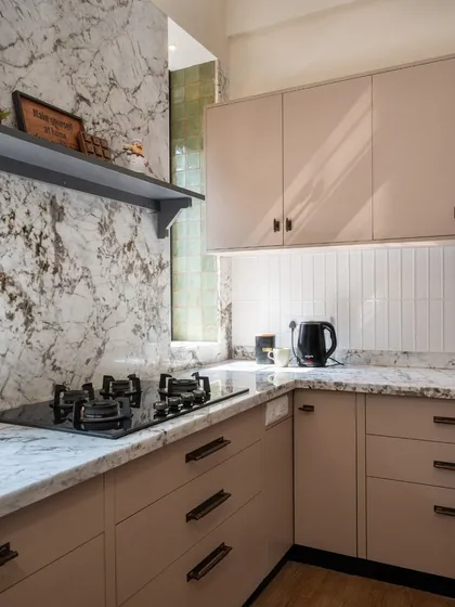 A small kitchen that is rich in character. The soft blush cabinets, marble-look quartz, and vertical white tiles create a space that feels calm, bright, and thoughtfully designed.
