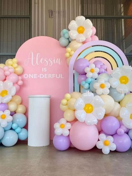 A "one-derful" first birthday party with a daisy and rainbow theme, using pastel balloons to create a cheerful and sweet atmosphere.