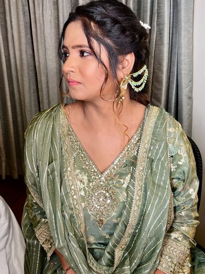 A side view of the minimal Mehendi makeup, paired with an elegant, messy bun and statement earrings.