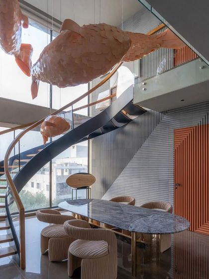 The sculptural fish chandelier is the undeniable centerpiece of the home, interacting with the spiral staircase to create a sense of movement and artistry.