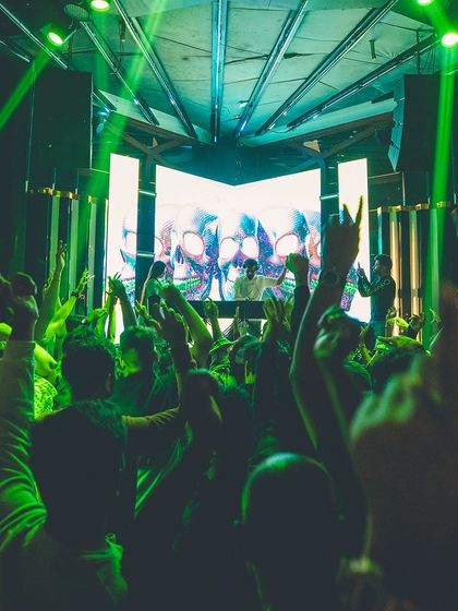 The crowd at Flo with their hands up, bathed in green laser lights. The lighting design is crucial for creating an immersive atmosphere.