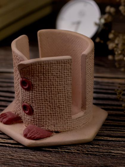 A minimalist shot of the empty pen stand, focusing on its unique shape and the texture of the clay and jute. The simple composition allows the artisanal quality of the piece to shine.
