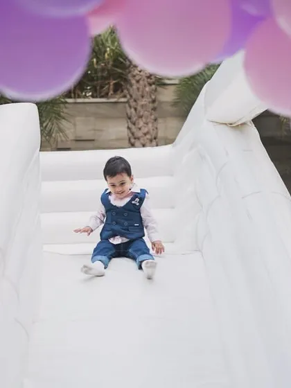 A perfect view from the top of the slide, framed by festive balloons, as a child gets ready to slide down.