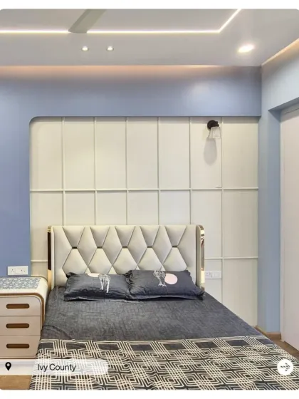 A chic bedroom with a tufted headboard and a white paneled accent wall. The light blue wall color adds a refreshing and calming touch.