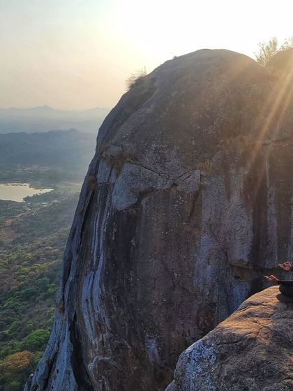 Akash in a moment of peace, meditating on a cliff edge with a beautiful view. Climbing offers not just physical challenges but also moments of profound connection with nature.