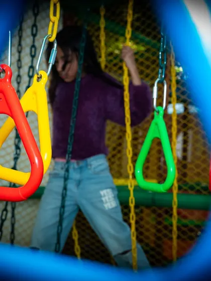 A peek through the structure at a girl navigating the hanging rings. The entire course is designed to be challenging but achievable for a wide range of ages.