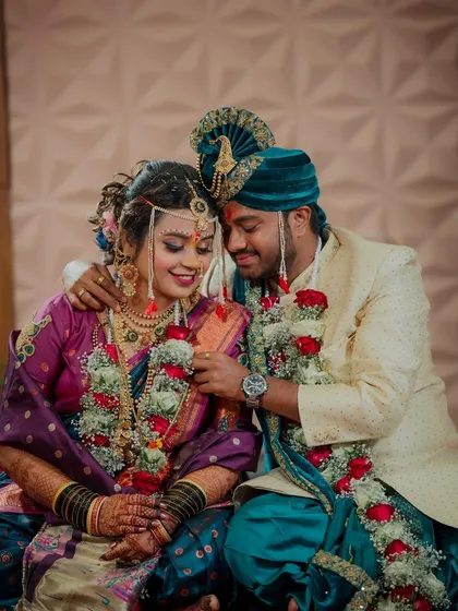 Capturing the quiet, intimate moments amidst the wedding day buzz. The groom gently adjusts his bride's garland, a small act of care that speaks volumes about their connection.