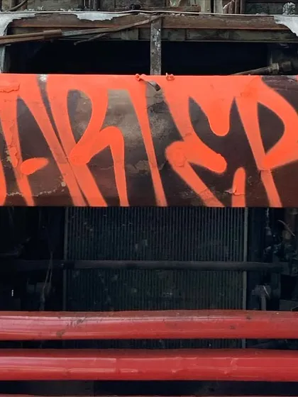 A bold orange throw-up on the front of a burnt-out truck. Finding unique spots and surfaces is part of the game.