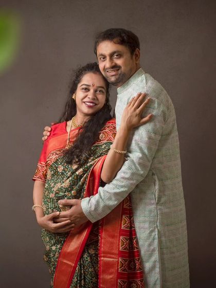 A traditional maternity portrait celebrating heritage. The beautiful saree and the couple's warm embrace create a picture of love and cultural pride.