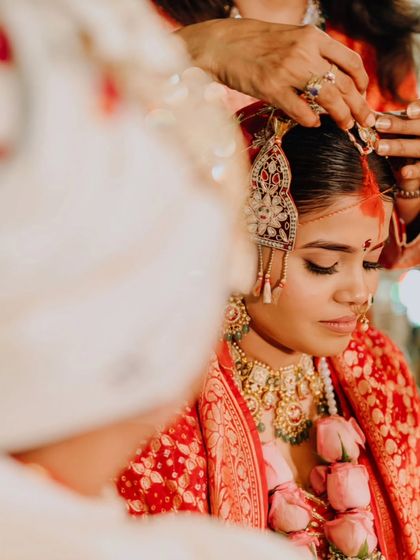 A close-up of a ritual during Eesha's wedding, showing the gentle placement of the bridal adornments, a moment of quiet focus and tradition.