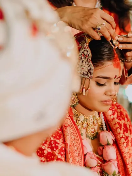 A close-up of a ritual during Eesha's wedding, showing the gentle placement of the bridal adornments, a moment of quiet focus and tradition.