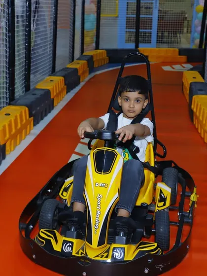 A little boy gets comfortable in his yellow go-kart, ready to experience the fun of our indoor racing circuit.