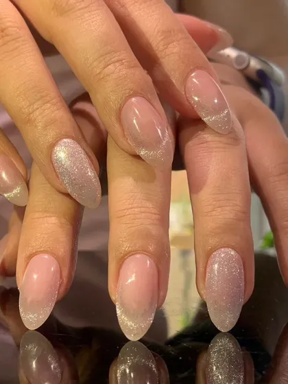 A delicate and shimmery manicure with a fine silver glitter polish and cat-eye effect accents.