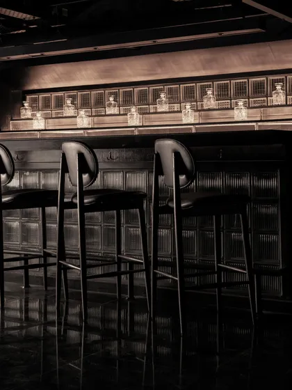 The back bar, where bottles are displayed against illuminated glass blocks, creating a glowing grid in the darkness.