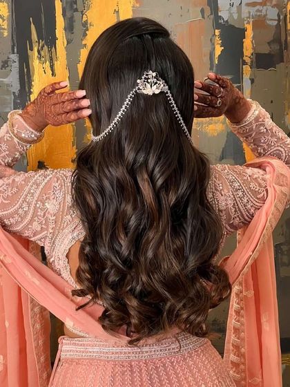 This elegant engagement hairstyle features soft waves in a half updo, adorned with a delicate, dangling hair accessory. It's a regal and sophisticated look for a special ceremony.