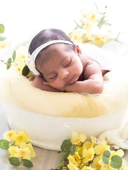 This little one is sleeping so peacefully in a butter-yellow nest. The bright, cheerful flowers add a touch of sunshine to this newborn portrait.