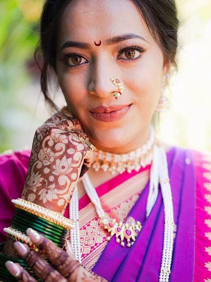 A close-up portrait focusing on the bride's beautiful mehendi and traditional green bangles. Her calm expression and the intricate details of her attire showcase Maharashtrian bridal elegance.