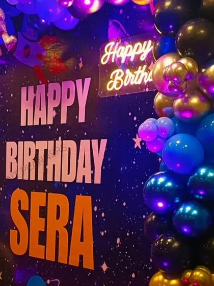 A close-up of the astronaut-themed birthday backdrop and neon sign.