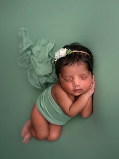 A simple and beautiful side-lying pose on a soft green background. The flowing fabric adds a touch of movement and elegance.